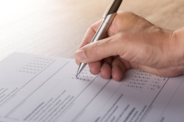 main d'homme tenant un stylo qui coche une case sur un questionnaire