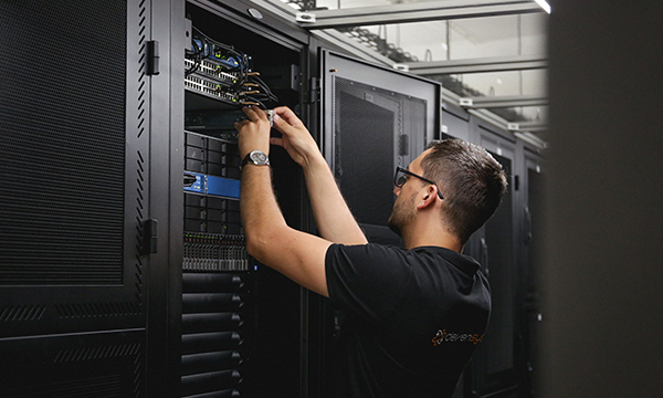 technicien en train d'installer du matériel, serveur, firewall etc... dans un data center.