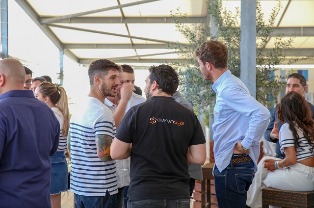 Une collaborateur de DEVENSYS de dos en train de parler avec des clients sur la terrasse d'une plage privée